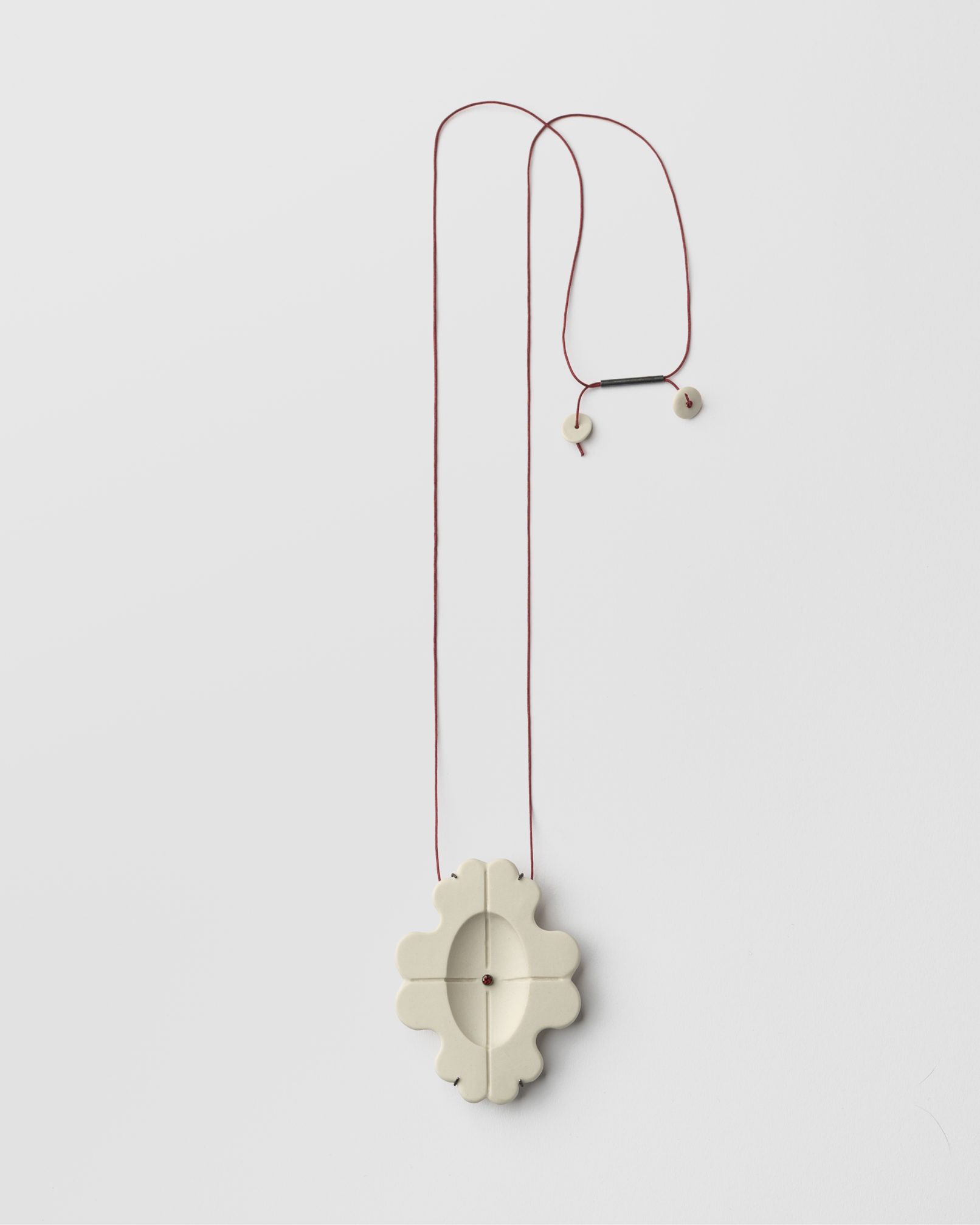 Joieria contemporània. Penjoll de porcellana, plata i granar. Projecte simetria. Dissenyat i creat per la joiera Marta Ortí. Terrassa, Barcelona.