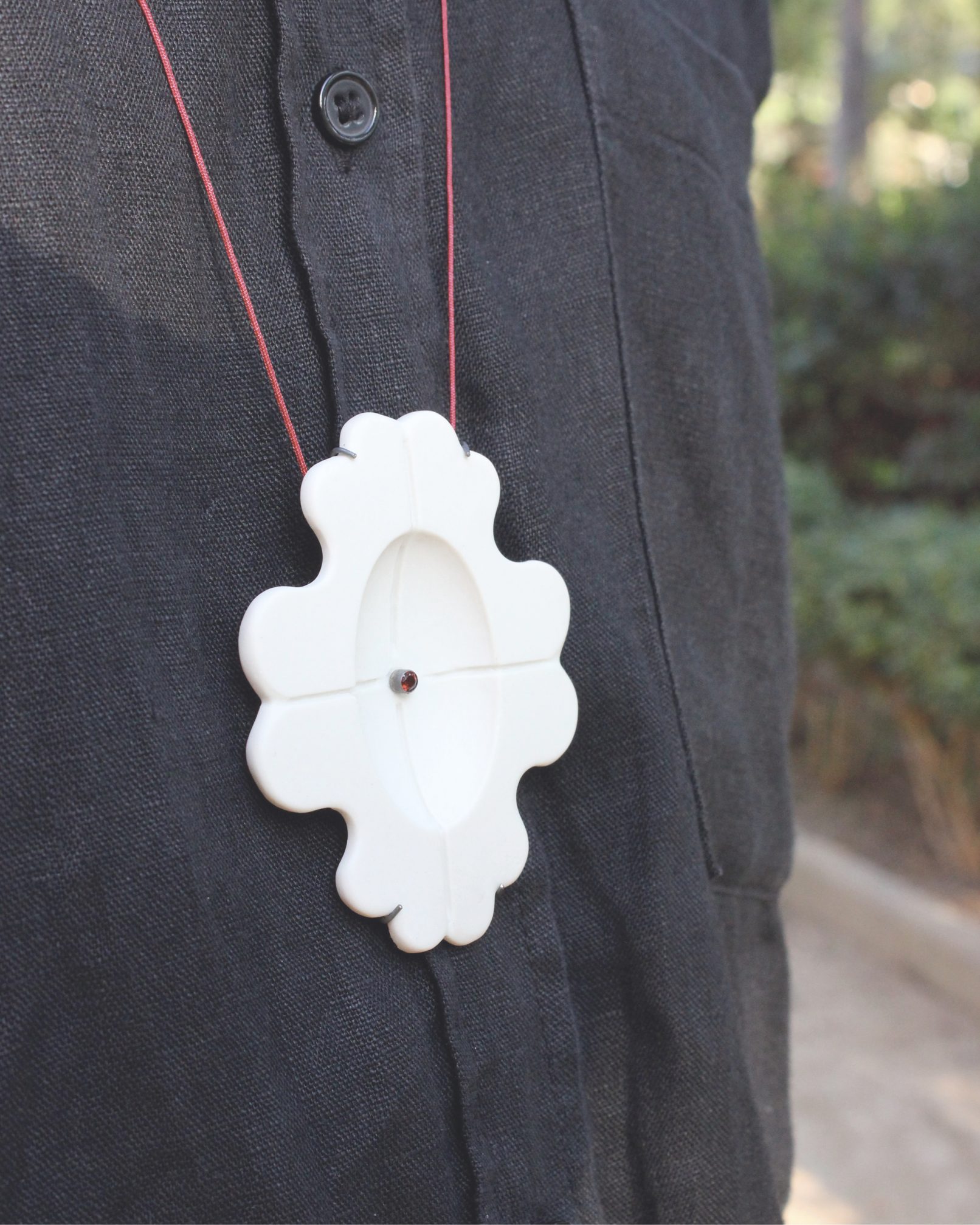 Joieria contemporània. Penjoll de porcellana, plata i granar. Projecte simetria. Dissenyat i creat per la joiera Marta Ortí. Terrassa, Barcelona.