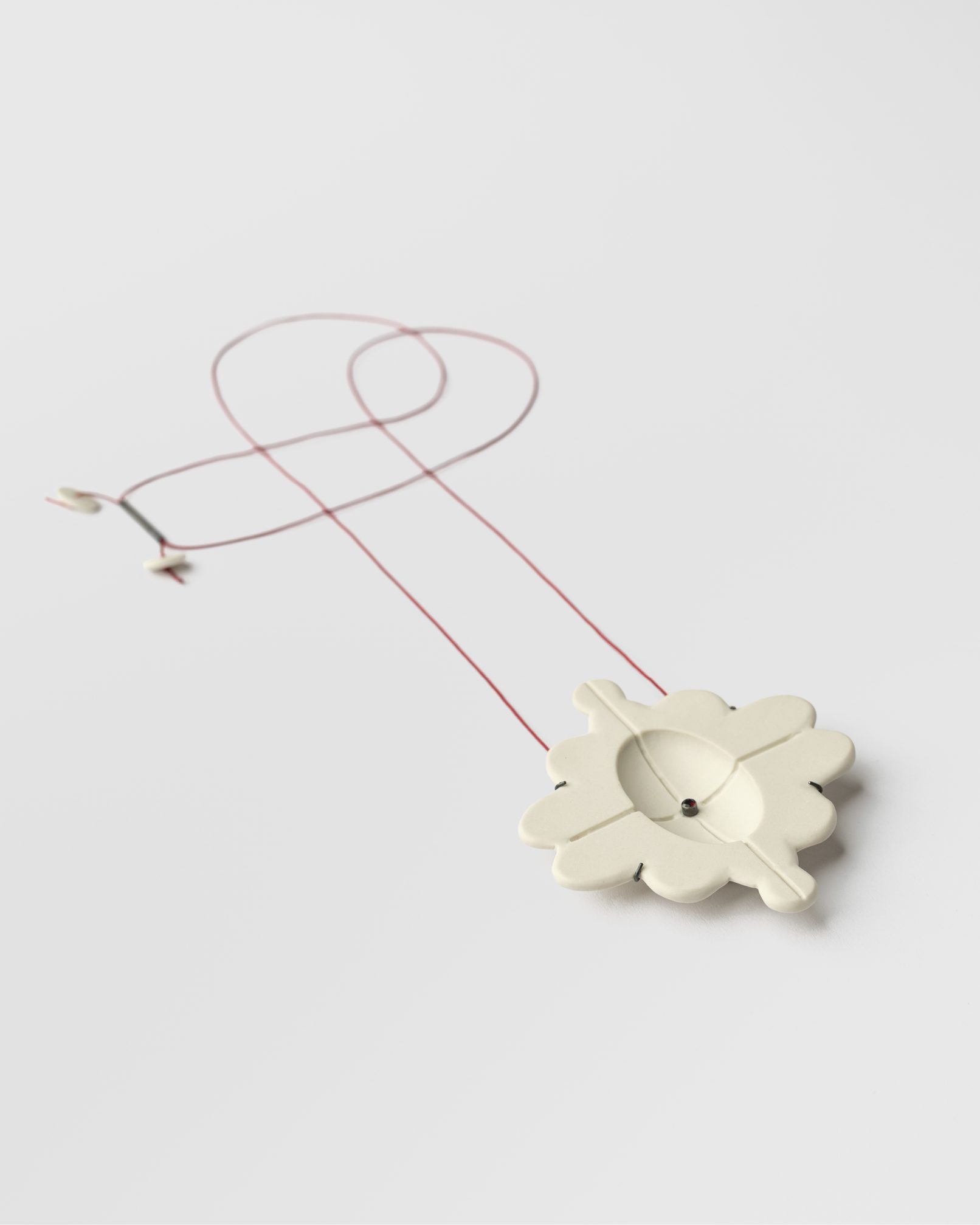 Joieria contemporània. Penjoll de porcellana, plata i granar. Projecte simetria. Dissenyat i creat per la joiera Marta Ortí. Terrassa, Barcelona.