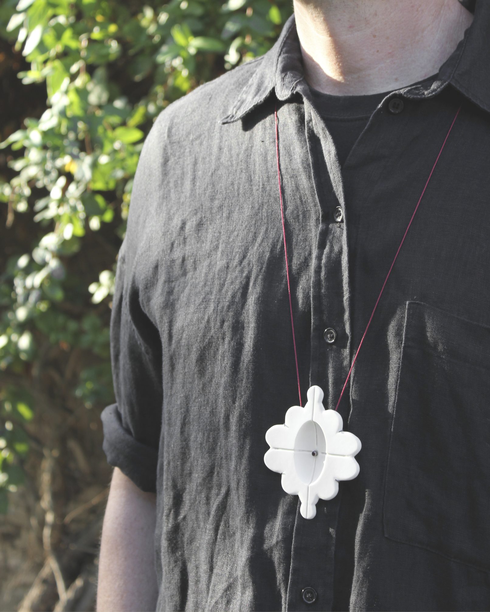 Joieria contemporània. Penjoll de porcellana, plata i granar. Projecte simetria. Dissenyat i creat per la joiera Marta Ortí. Terrassa, Barcelona.